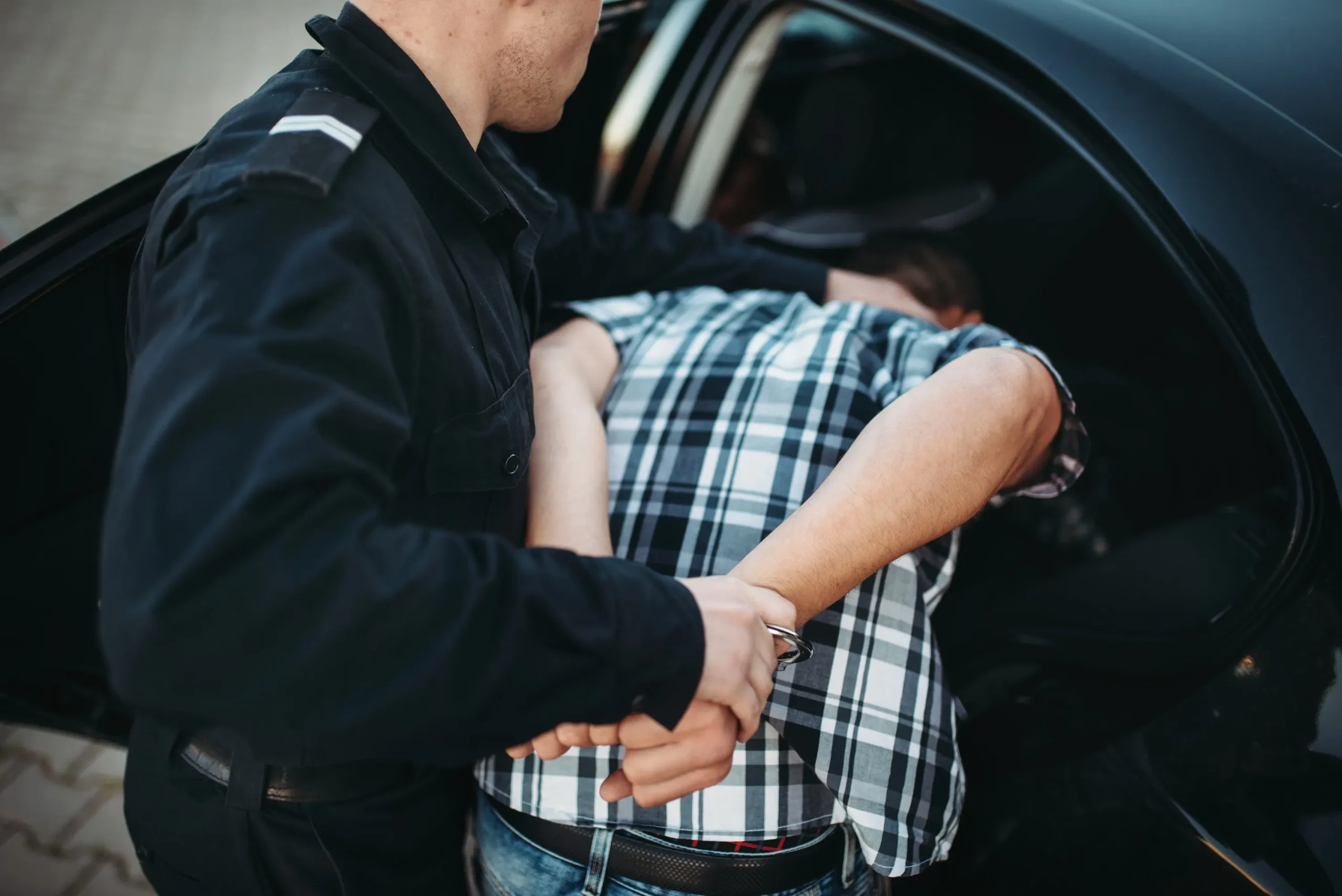 A police officer arresting someone and putting them in the car.